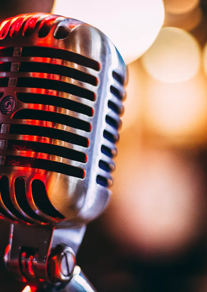 A close-up of a vintage microphone surrounded by soft glowing lights, inviting visitors to listen.