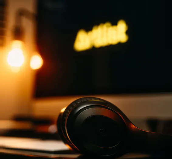 A cozy studio corner with headphones resting on a wooden desk beside a laptop.