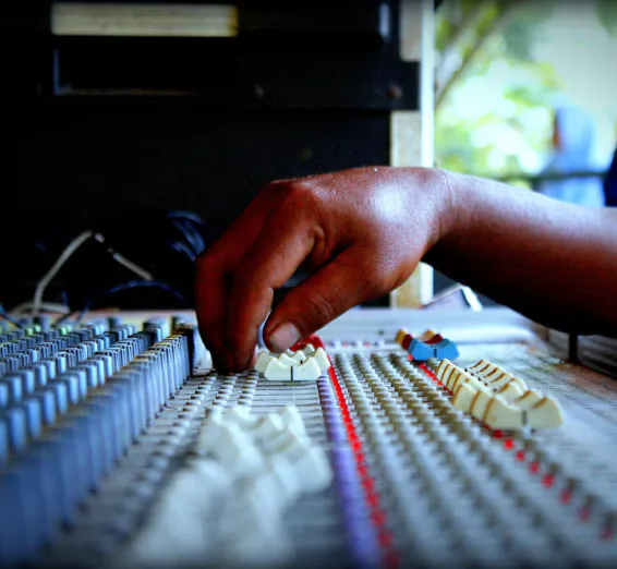 Hands adjusting sound levels on a mixing console, capturing the essence of audio control.